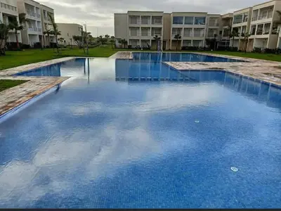 a large pool of blue water in front of a building at Villa avec piscine, Hacienda Beach Sidi Rahal in Sidi Rahal