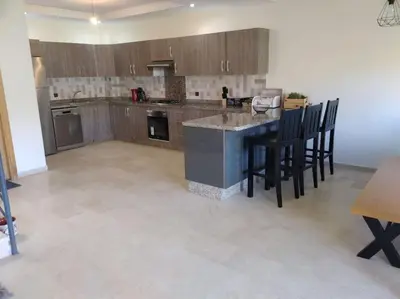 a kitchen with a counter and chairs in a room at Villa avec piscine, Hacienda Beach Sidi Rahal in Sidi Rahal