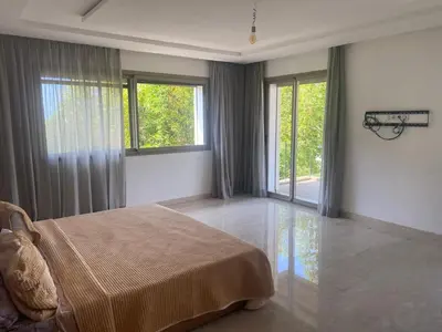 a bedroom with a bed and large windows at Villa avec piscine Mohammedia in Mohammedia
