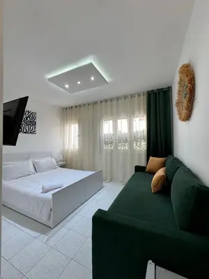 a bedroom with a bed and a green couch at SUITOUISS - Agdal - Studio en plein cœur de Rabat à 5 minutes du grand mall Arribat Center - centre ville in Rabat