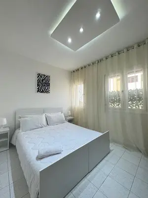 a white bedroom with a large bed and a window at SUITOUISS - Agdal - Studio en plein cœur de Rabat à 5 minutes du grand mall Arribat Center - centre ville in Rabat