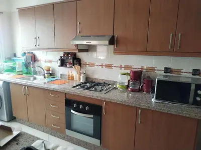 a kitchen with wooden cabinets and a stove top oven at Paradis Avec Vue Harhoura in El Harhoura
