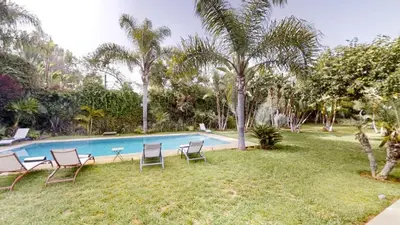 a yard with chairs and a swimming pool at Villa F- Luxury 4 suites on a 5000sqm in the heart of Ambassadeurs in Rabat