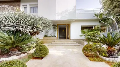 a house with a courtyard with trees and plants at Villa 44- Superbe Villa Moderne 7 chambres, 2500m2, piscine, cinema, clim , meublee in Rabat