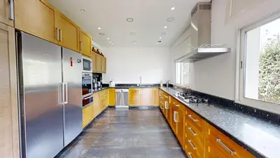 a large kitchen with wooden cabinets and a stainless steel refrigerator at Villa 44- Superbe Villa Moderne 7 chambres, 2500m2, piscine, cinema, clim , meublee in Rabat