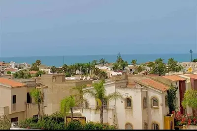 a city with buildings and palm trees and the ocean at Paradis Avec Piscine et Vue sur mer Harhoura in Temara