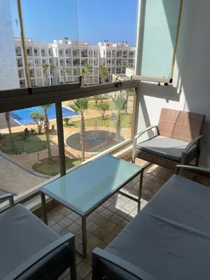 a balcony with a table and chairs in a building at Grand appartement vue sur piscine Bouznika in Kasba Bou Hamira