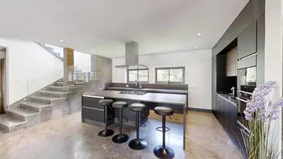 a kitchen with a counter with a sink and stools at Villa S- Luxurious 8 masterbedrooms villa on 3000m2, close to all amenities, Golf and heart of Souissi in Rabat