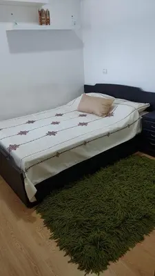 a bed in a room with a green rug at Sweet home in Dar Bouazza