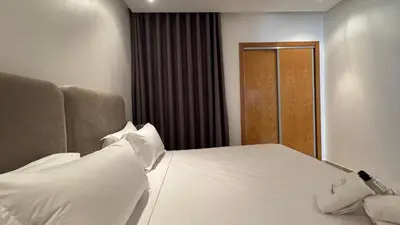 a bedroom with a white bed and a wooden door at Street view 2BR Terrace - AppartAli Luxury Platform in Casablanca
