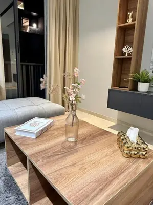 a vase of flowers on a wooden table in a living room at Studio Lilas CFC in Casablanca