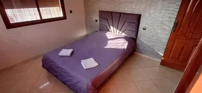 a bed with purple sheets in a room with a window at Appartement très propre et calme in Bouznika