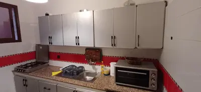 a kitchen with white cabinets and a sink and a microwave at Appartement très propre et calme in Bouznika