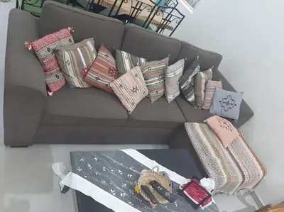 a gray couch with pillows on it with a table at Espace de détente in Bouznika