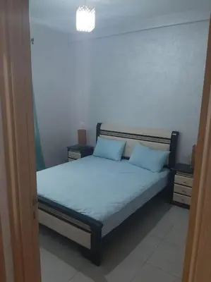 a bed with two blue pillows in a room at Espace de détente in Bouznika