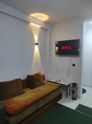 a room with a couch and a tv on the wall at Appartement 5 min à gare Bouskoura & Hôpital Mohamed 6 in Bouskoura
