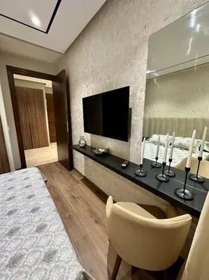 a bedroom with a bed and a television and a chair at Studio Jasmin CFC n 15 in Casablanca