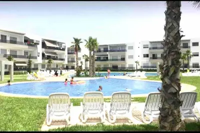 a group of chairs sitting around a swimming pool at 2 bedroom appart at the beach in gated community with pool in Sidi Rahal