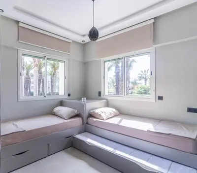 two beds in a room with two windows at L Évasion ZEN Duplex d Exception Entre Plage et Serenite in Mohammedia