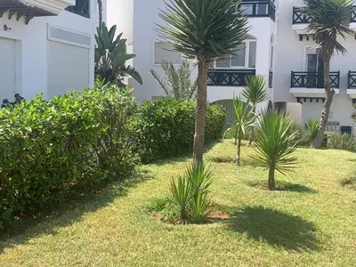 a yard with palm trees in front of a building at Appartement en bord de mer dans une résidence fermée in Casablanca