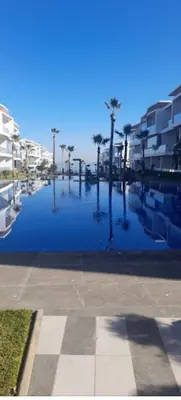 a pool of water with palm trees and buildings at Dar Bouazza getaway in Tamaris