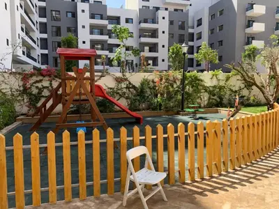 a chair sitting in front of a fence with a playground at Duplex Zenata Tower in Aïn Harrouda