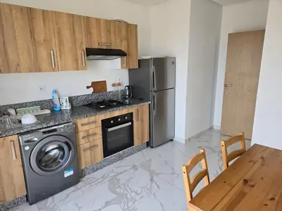 a kitchen with a stainless steel refrigerator and a table at Duplex Zenata Tower in Aïn Harrouda