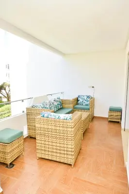 a living room with wicker couches and a balcony at Modern Marina - Beach - Pool in Sidi Rahal