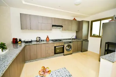 a kitchen with wooden cabinets and a washer and dryer at Modern Marina - Beach - Pool in Sidi Rahal