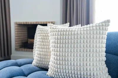 two white pillows sitting on a blue couch with a fireplace at Résidence Luxe avec Plage Privée in Bouznika