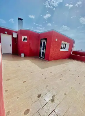 a red house with a large empty patio at Confort Moderne à 2 Pas de la Mer Calme Absolu in Dar Bouazza