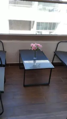 a vase of flowers sitting on a glass table at Beachside Apartment in Mohammedia