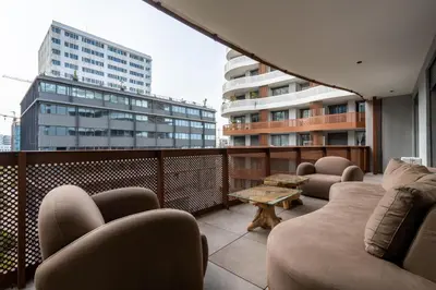 a balcony with couches and a table and buildings at Élégance Urbaine Casa Finance city in LʼOasis