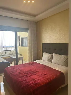 a bedroom with a large bed with a red blanket at Appartement location in Bouznika