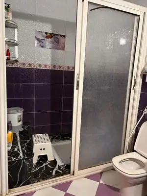 a bathroom with a glass shower door and a toilet at Maison wafaa in O Ben Slimane