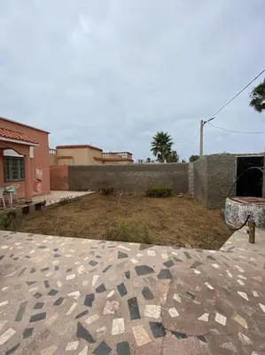 a stone patio with a fireplace in a yard at Villa Casablanca-Sidi Rahal à 5 min de la plage in Sidi Rahal