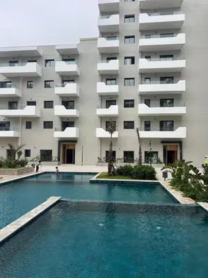 a swimming pool in front of a large building at Trendy Condo - Stunning Views in Aïn Harrouda
