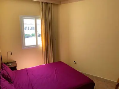 a bedroom with a purple bed and a window at Résidence beach house in Dar Bouazza