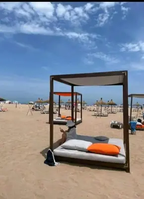 a group of beds on a beach with the ocean at Cosy Apartment with sea view in Sidi Rahal