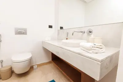 a white bathroom with a sink and a toilet at Luxury 2BR Apartment in Agdal for a Relaxing Stay in Es Souissi