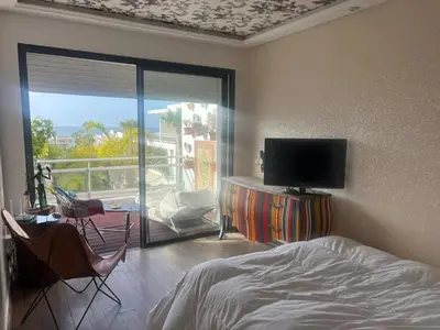 a bedroom with a bed and a tv and a balcony at Eden in Dar Bouazza