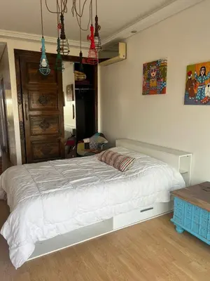 a bedroom with a white bed and a wooden floor at Eden in Dar Bouazza