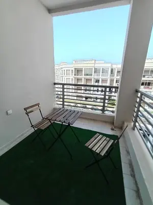 two chairs on a balcony with a view of a building at Magnifique appart vue piscine 5min de la plage in Kasba Bou Hamira