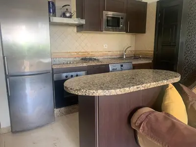 a kitchen with a granite counter top and a refrigerator at Beach apartment in Dar Bouazza
