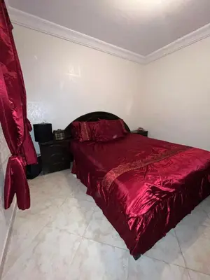 a bedroom with a bed with a red comforter at Appart meublé 5min de la plage à Bouznika in Bouznika