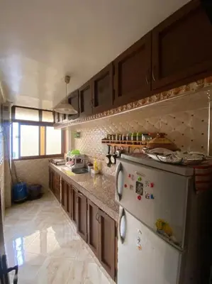 a kitchen with a white refrigerator and wooden cabinets at Appartement Neo in Oulad Hamida