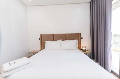 a bedroom with a bed with white sheets and a window at Casa Streets 3 BR Terrace - AppartAli Luxury Platform in Casablanca