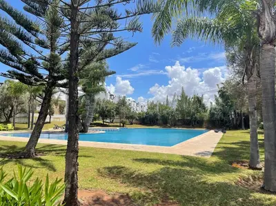 a swimming pool in a park with palm trees at Eden Island Bouznika Bel appartement avec jardin in Bouznika
