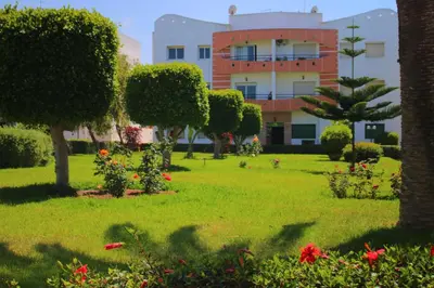a park in front of a building with trees and flowers at Mohammedia 2 in Mohammedia