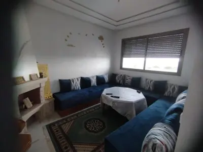 a living room with a blue couch and a table at appartement jinane in Bouznika